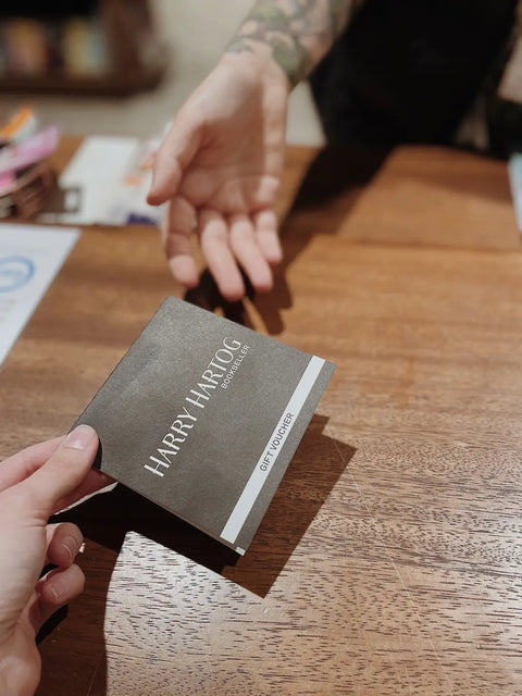 A Harry Hartog gift voucher being passed from a bookseller to a customer